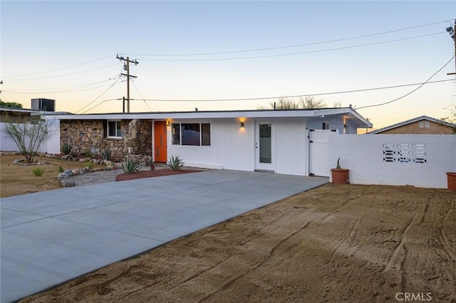 single story home featuring stone siding, fence, and stucco siding