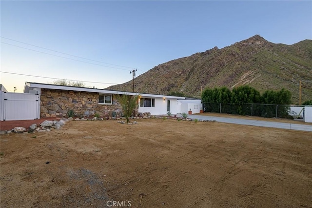 view of front of property featuring stone siding, fence, and a mountain view