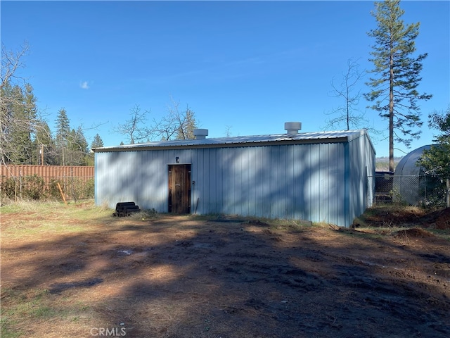 exterior space featuring metal roof, an outbuilding, a pole building, and fence