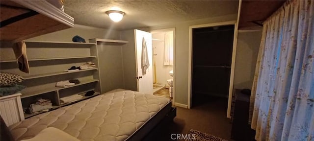 bedroom featuring dark colored carpet, ensuite bathroom, and a textured ceiling