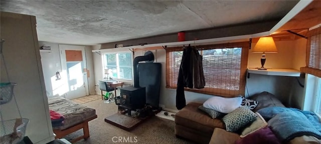 living area with a wood stove, a textured ceiling, and carpet flooring