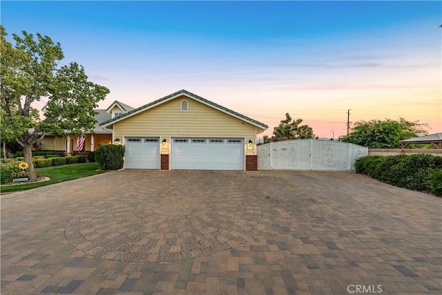 view of front of house featuring decorative driveway, a gate, brick siding, and a garage