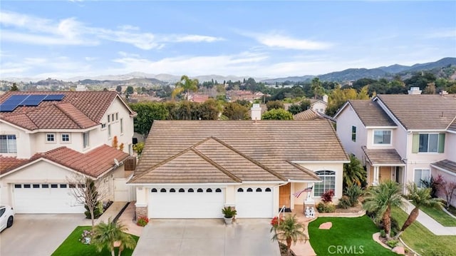 view of front of house featuring a tile roof, concrete driveway, and a mountain view