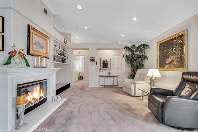 sitting room featuring a glass covered fireplace, carpet, visible vents, and ornamental molding