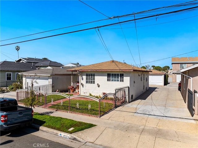 view of front facade featuring stucco siding, a fenced front yard, an outdoor structure, a front yard, and a garage