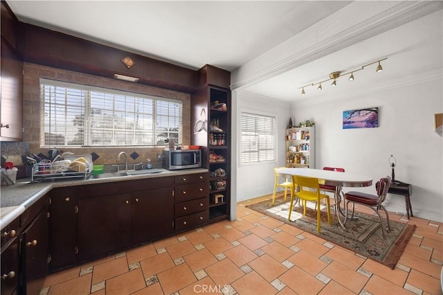 kitchen with decorative backsplash, stainless steel microwave, light countertops, and ornamental molding