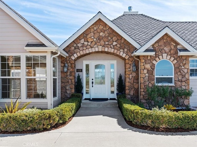 property entrance with stone siding and roof with shingles