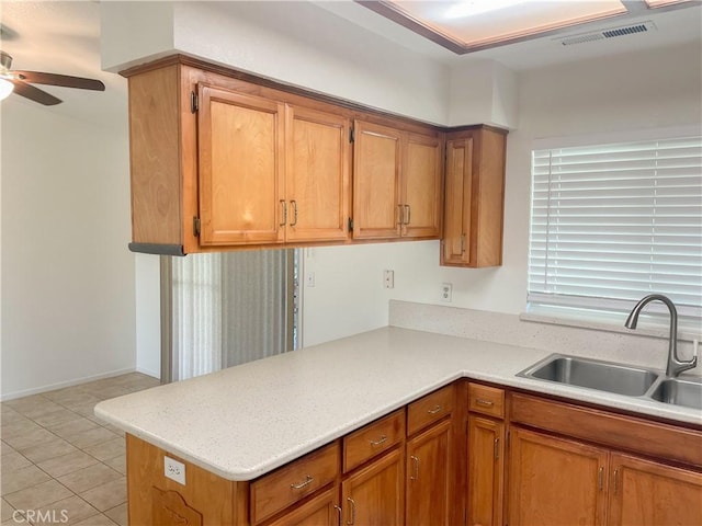 kitchen with light countertops, brown cabinetry, a sink, and visible vents