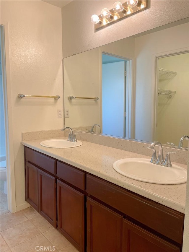 bathroom featuring tile patterned flooring, a sink, toilet, and double vanity