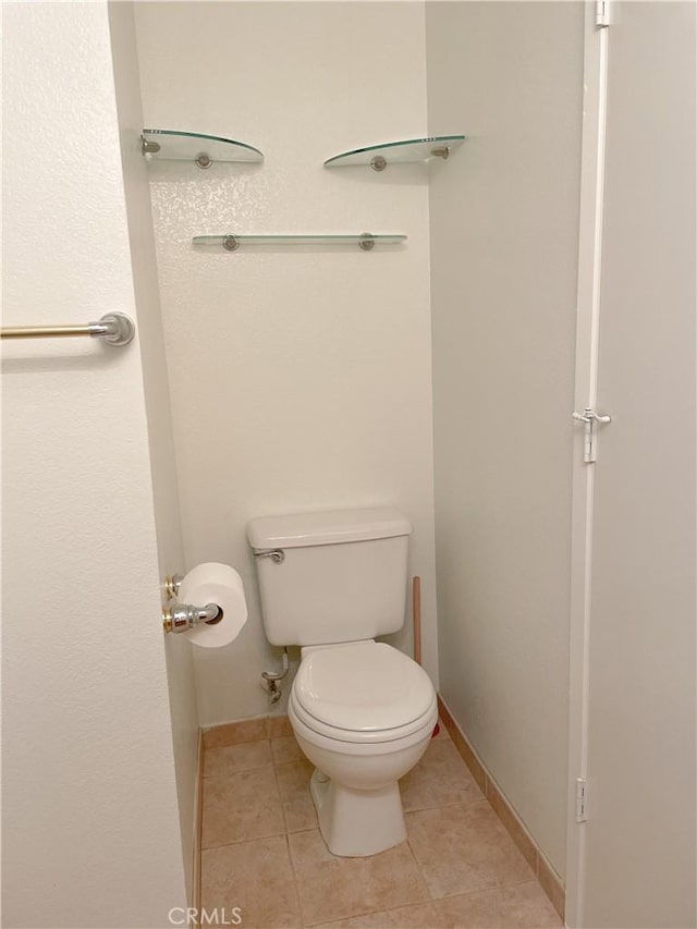 bathroom featuring tile patterned flooring, toilet, and baseboards