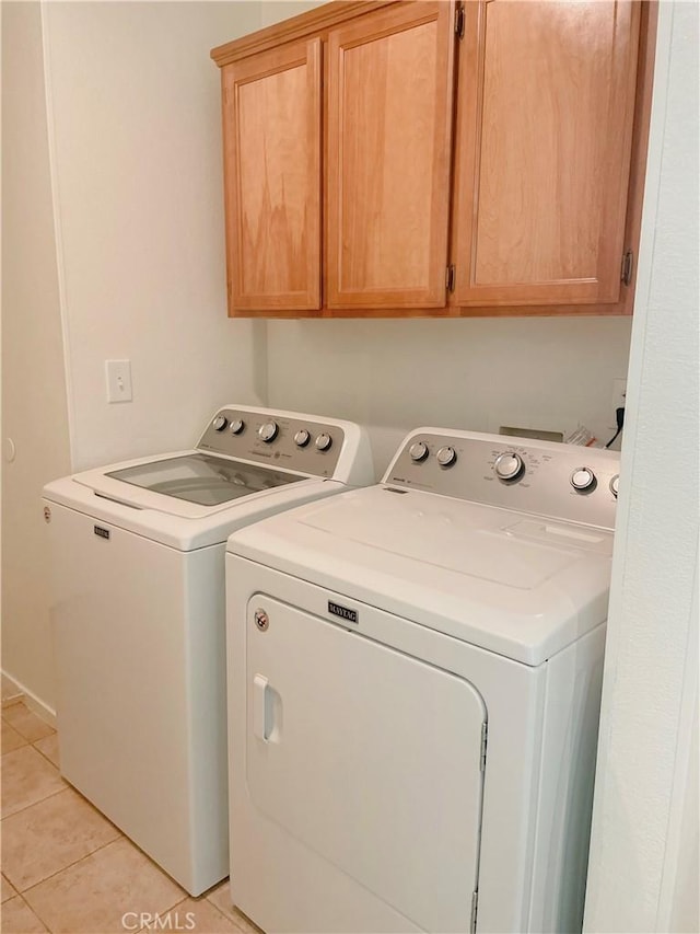 clothes washing area with cabinet space, light tile patterned flooring, and independent washer and dryer