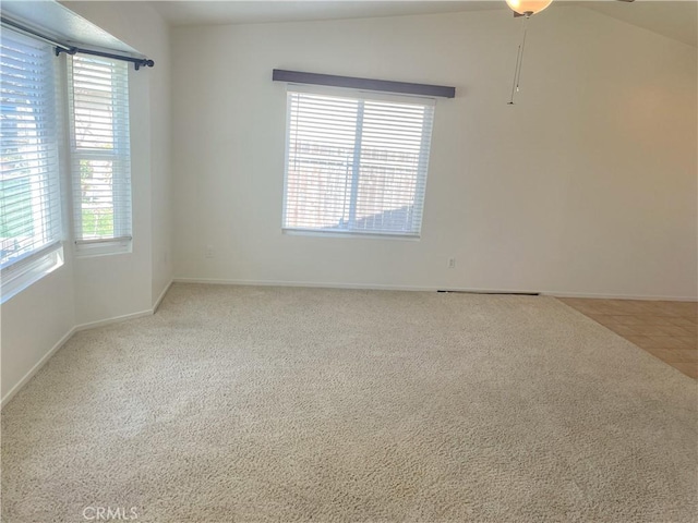 carpeted spare room with lofted ceiling, baseboards, and tile patterned floors