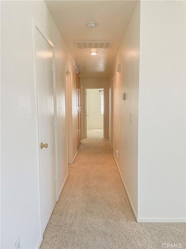 hall with baseboards and visible vents