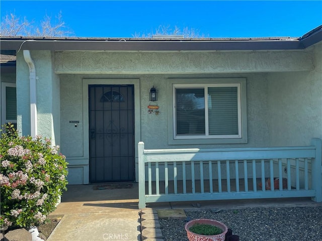 property entrance featuring a porch and stucco siding