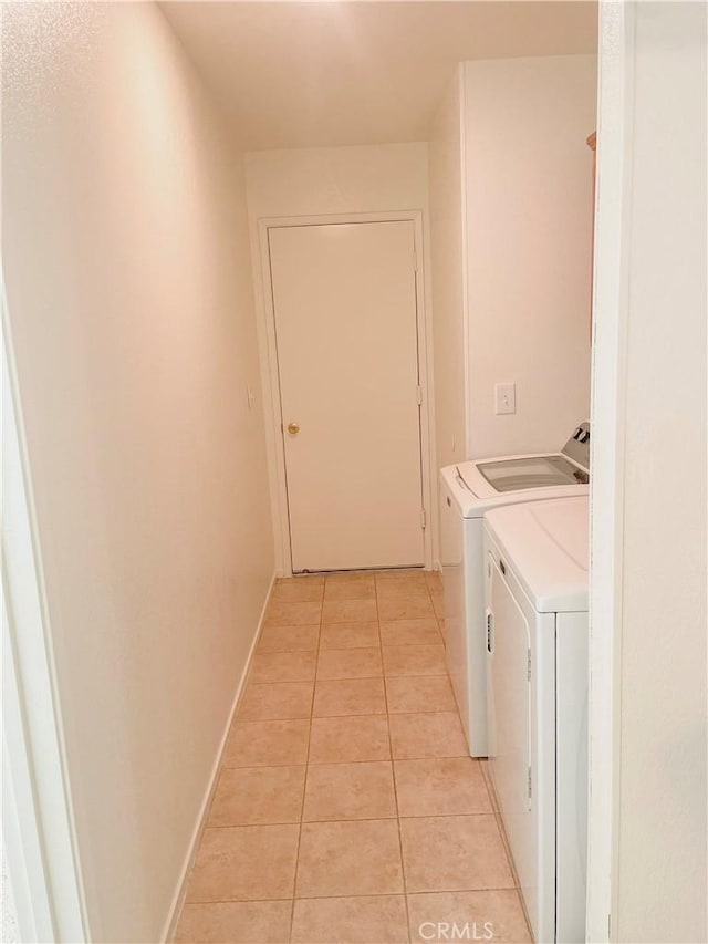 clothes washing area with laundry area, baseboards, washing machine and clothes dryer, and light tile patterned floors