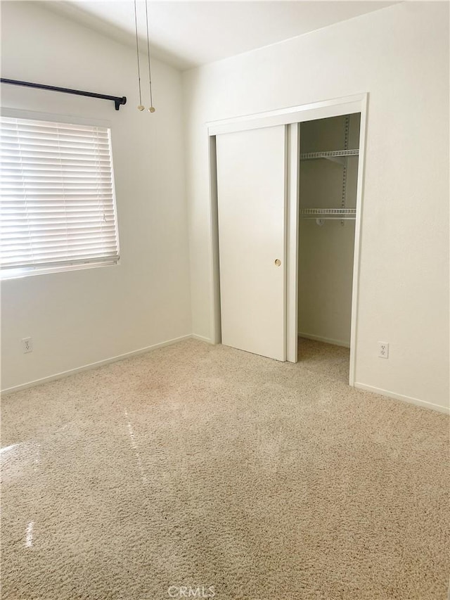 unfurnished bedroom with a closet, carpet, and baseboards