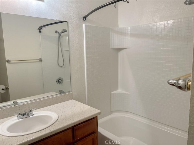 full bath with a textured wall, vanity, and bathing tub / shower combination