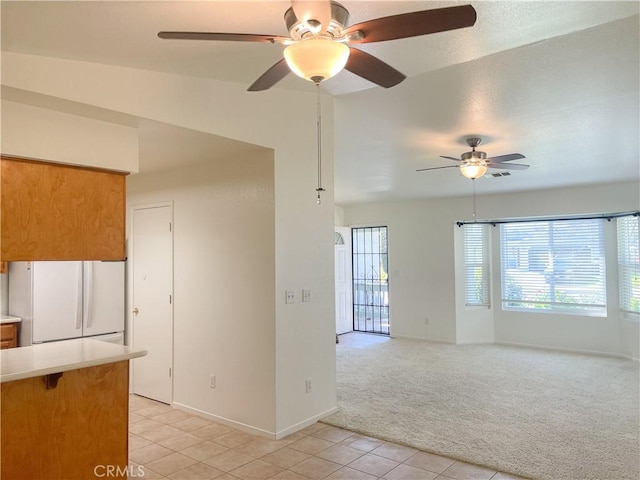 interior space featuring light tile patterned flooring, light carpet, baseboards, light countertops, and freestanding refrigerator