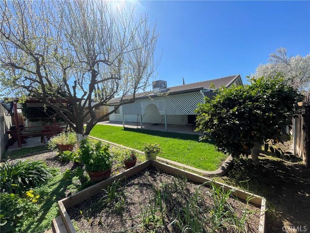 view of yard featuring central AC unit, a patio area, fence, and a vegetable garden