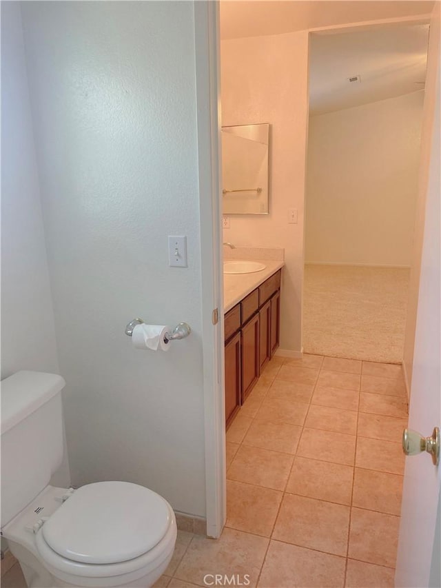 bathroom with toilet, tile patterned flooring, baseboards, and vanity