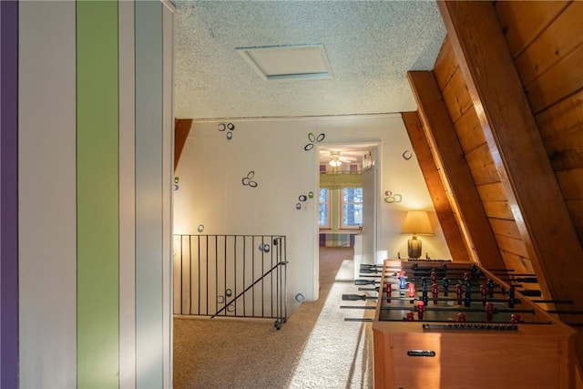 hallway featuring an upstairs landing, carpet, and a textured ceiling