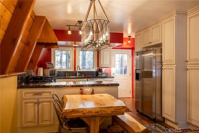 kitchen with cream cabinetry, appliances with stainless steel finishes, an inviting chandelier, and a sink