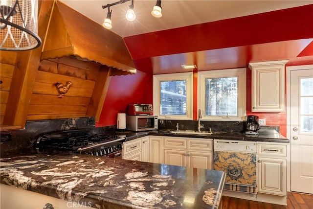 kitchen featuring a sink, stainless steel microwave, cream cabinets, gas stove, and dishwasher