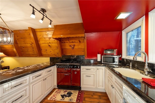 kitchen featuring stainless steel microwave, decorative light fixtures, white dishwasher, dark wood-style floors, and a sink