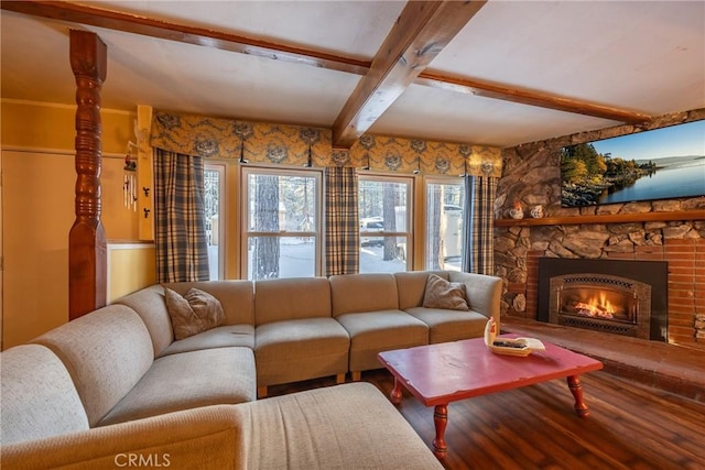 living room featuring beam ceiling, a stone fireplace, and wood finished floors