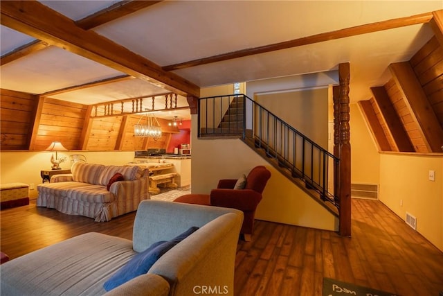 living area with visible vents, wood finished floors, vaulted ceiling with beams, and stairway