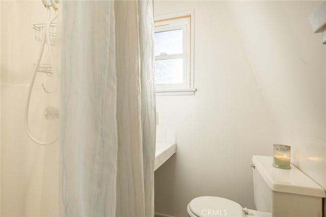 bathroom with a shower with curtain, toilet, and baseboards