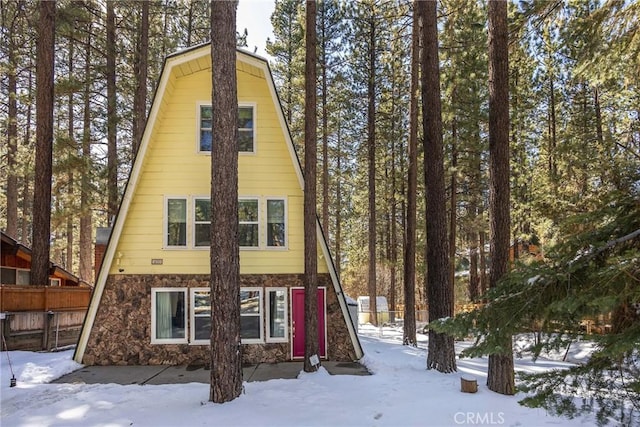 view of front of house featuring stone siding and fence