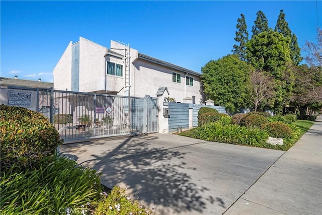 exterior space featuring a gate, fence, and stucco siding