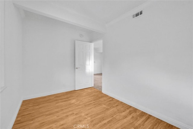 spare room with light wood-style floors, visible vents, and baseboards