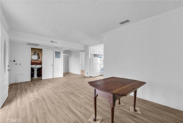 interior space with light wood-type flooring, visible vents, crown molding, and a textured ceiling