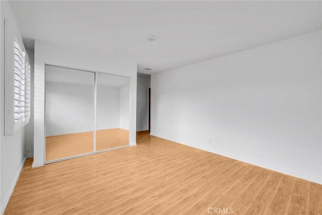 unfurnished bedroom featuring a closet and light wood finished floors