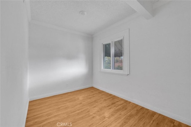 spare room with light wood-type flooring, a textured ceiling, and baseboards