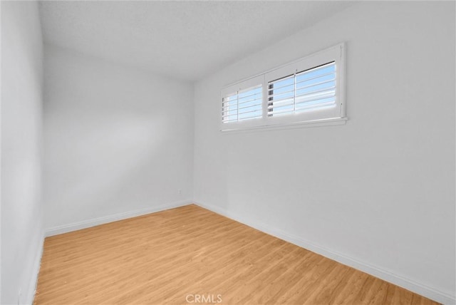 empty room featuring light wood-type flooring and baseboards