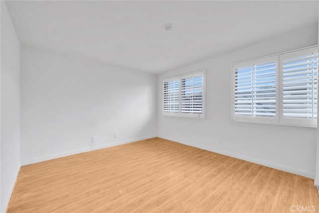 empty room featuring light wood-type flooring and baseboards