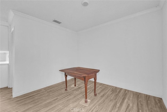 unfurnished room featuring light wood-type flooring, visible vents, crown molding, and baseboards