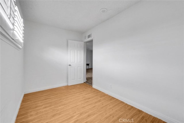 spare room featuring baseboards, visible vents, and light wood-style floors