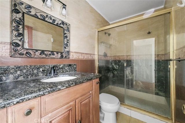 full bathroom with toilet, a stall shower, tile walls, and vanity