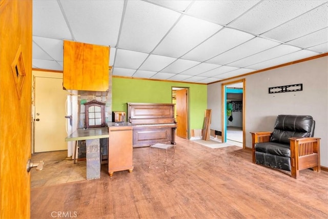 kitchen with a paneled ceiling, a peninsula, wood finished floors, open floor plan, and ornamental molding