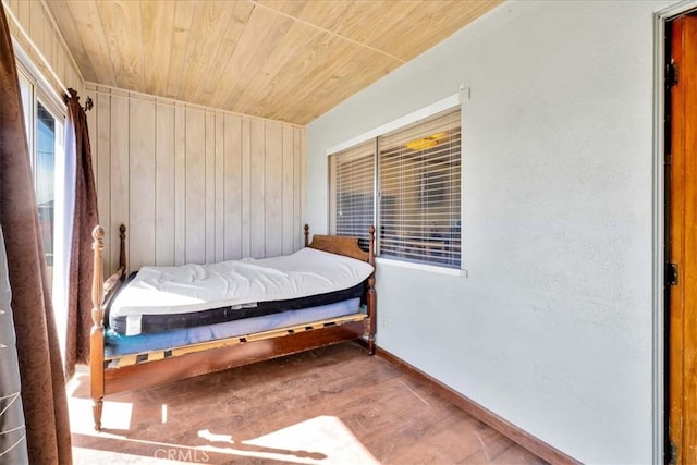 bedroom featuring baseboards, wood finished floors, wood ceiling, and wooden walls