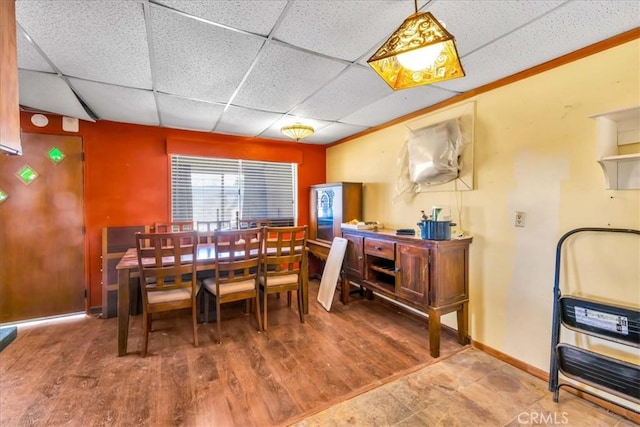 dining room featuring a paneled ceiling, baseboards, and wood finished floors