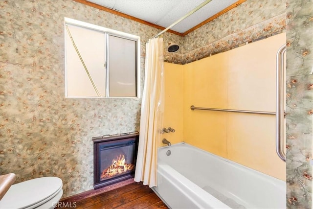 bathroom with shower / tub combo, wallpapered walls, wood finished floors, and a glass covered fireplace