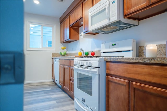 kitchen with white appliances, baseboards, brown cabinetry, and light wood finished floors