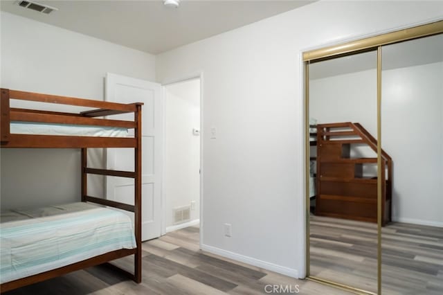 unfurnished bedroom featuring a closet, wood finished floors, visible vents, and baseboards