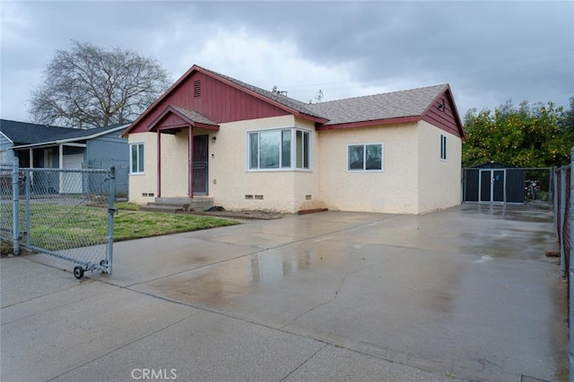 bungalow-style house featuring a shingled roof, crawl space, a gate, fence, and an outdoor structure