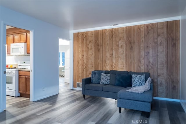 living area featuring baseboards, wood finished floors, and wooden walls